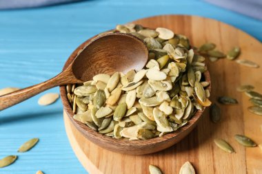 Mavi ahşap zemin üzerinde kabak tohumları olan bir kâse.