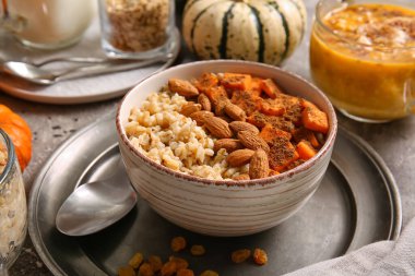 Bir kase lezzetli yulaf ezmesi, balkabağı ve arkaplanda badem.