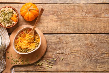 Tahta zemin üzerinde balkabağı olan bir kase lezzetli yulaf ezmesi