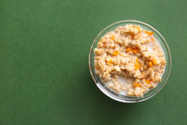 Bir kase lezzetli yulaf ezmesi ve yeşil arka planda balkabağı.