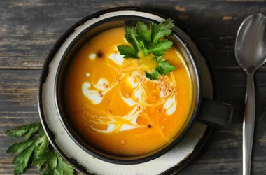 Ahşap arka planda balkabağı kremalı çorba, yakın plan.