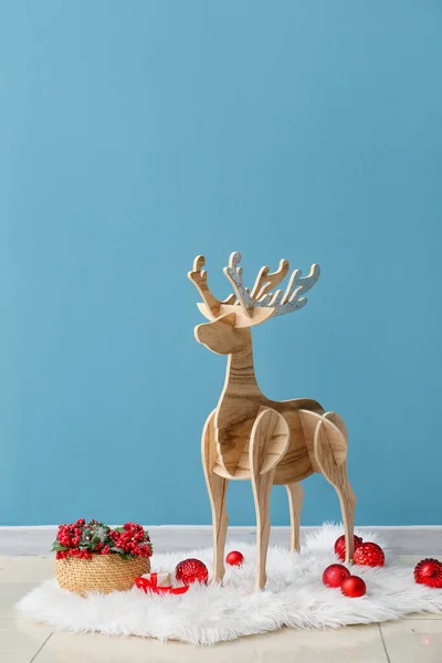 青い壁の近くにローワンとクリスマスボールと木製のトナカイ — ストック写真