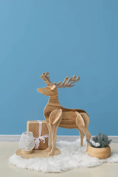 青い壁の近くのクリスマスプレゼント ランプとモミの枝を持つ木製のトナカイ — ストック写真