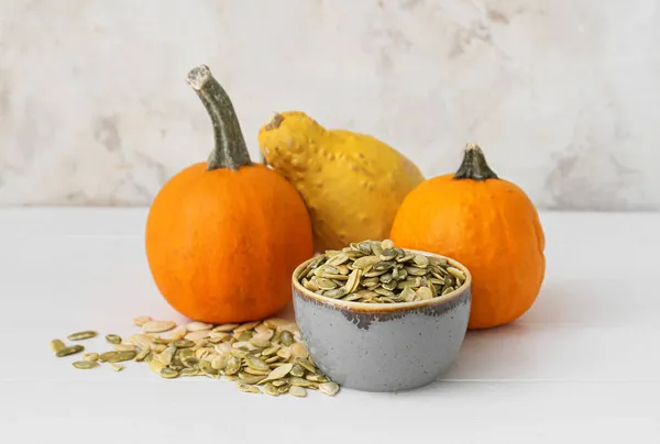 Bowl with pumpkin seeds and fresh vegetables on table