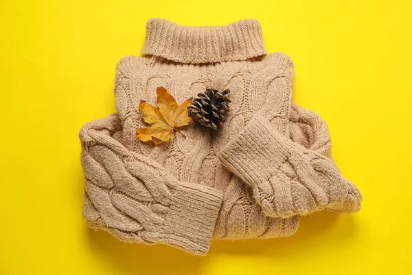 暖かいセーター 乾燥した葉と黄色の背景に松のコーン — ストック写真