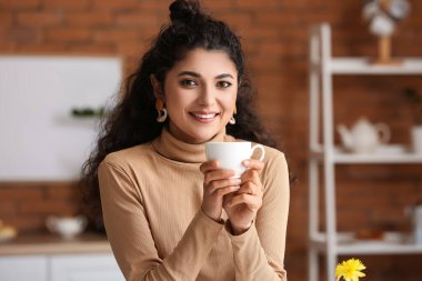 Evde çay içen güzel bir kadın.