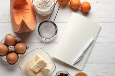 Beyaz ahşap arka planda balkabağı turtası tarifi ve malzemeleri.