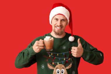 Bir fincan sıcak kakaolu yakışıklı adam, arka planda başparmağını kaldırıyor.