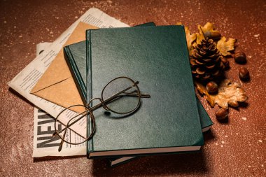 Renk arkaplanındaki kitap, gazete, zarf, gözlük ve sonbahar dekoru yığını