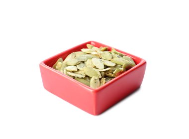 Beyaz arkaplanda kabak tohumları olan bir kase