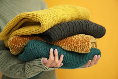 Kadın arka planda kalın süveter yığını tutuyor