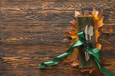 Ahşap zemin üzerinde masa düzenleme, kozalak ve sonbahar yaprakları ile kompozisyon