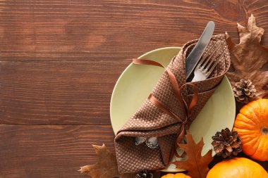 Ahşap zemin üzerinde masa düzenleme, balkabakları ve sonbahar yaprakları ile kompozisyon