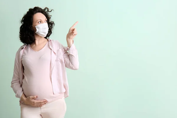 Young Pregnant Woman Medical Mask Pointing Something Color Background — Stock Photo, Image