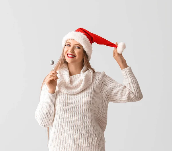 戴着圣诞礼帽 头戴灰色背景棒棒糖的年轻漂亮女人 — 图库照片
