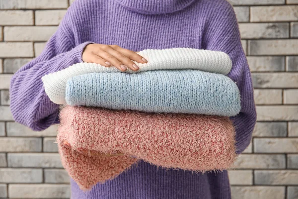 Woman Holding Stack Different Stylish Sweaters Brick Wall Background — Stock Photo, Image