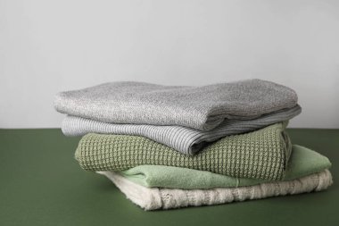 Gri arkaplana karşı yeşil masadaki farklı süveter yığını