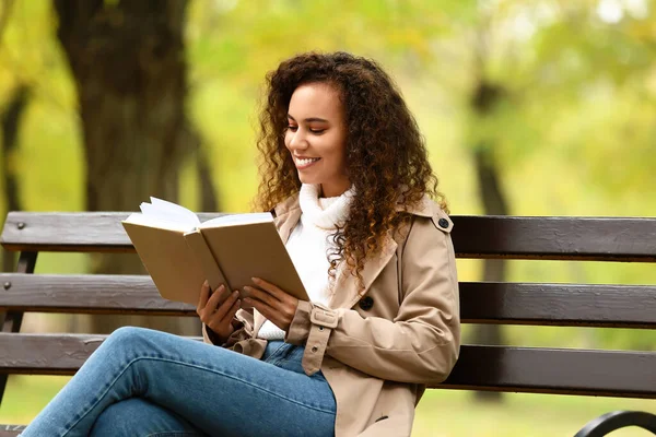 Gülümseyen Afro Amerikalı Kadın Sonbahar Parkında Kitap Okuyor — Stok fotoğraf