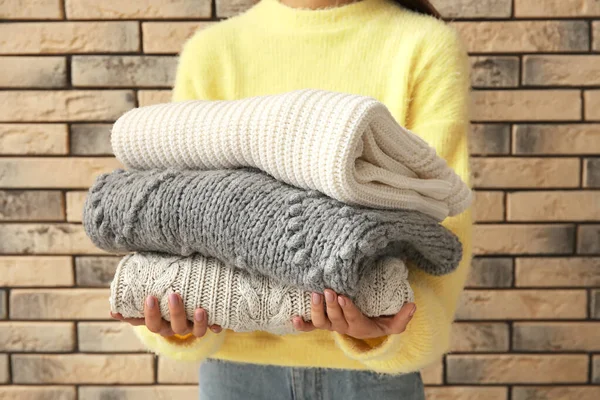 Woman Holding Stack Knitted Sweaters Brick Wall Background — Stock Photo, Image