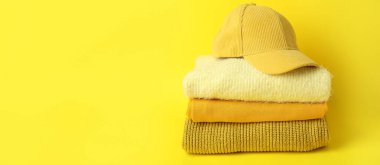 Sarı zemin üzerinde şık kış kıyafetleri yığını ve metin için boşluk