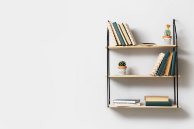 Işıklı duvarda kitap asılı modern raflar.
