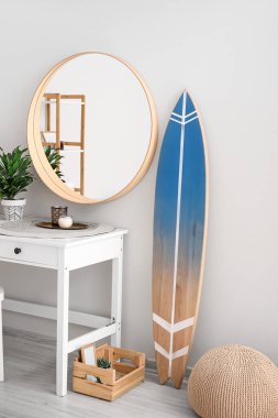 Sörf tahtası, masa ve aynalı modern bir oda.