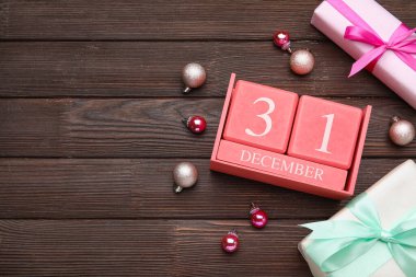 31 Aralık tarihli takvim, hediye kutuları ve ahşap arka planda Noel süsleri
