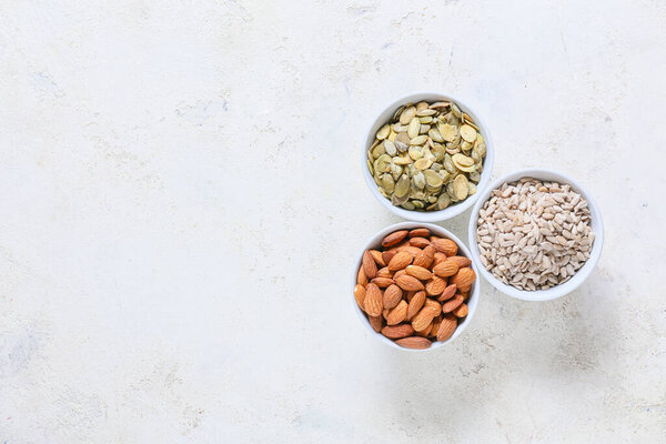 Bowls with sunflower, pumpkin seeds and almond nuts on grunge background