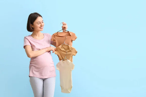 Ung Gravid Kvinna Med Baby Bodysuits Blå Bakgrund — Stockfoto