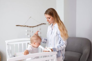 Evinde beşiğinde küçük sevimli bebeği olan genç bir anne.