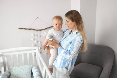 Genç anne oyuncak bebeğini kucağında tutuyor.