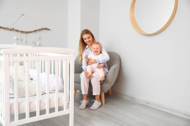 Genç anne ile evde koltukta oturan onun şirin bebek
