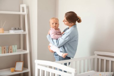 Genç anne yatak odasında bebeğini kucağında tutuyor.