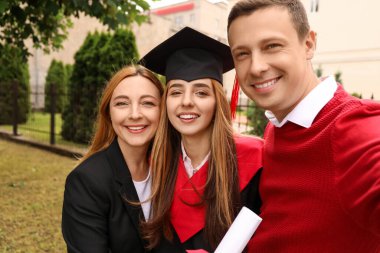 Mezuniyet gününde ailesiyle selfie çeken mutlu genç kadın