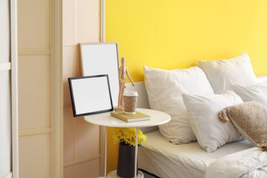 Çerçeveli masa, bir fincan kahve ve şık yatak odasında ahşap manken.