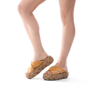 Beyaz arka planda modern sandaletli kadın bacakları, yakın plan.