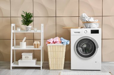 Çamaşır makinesi ve ahşap sepeti olan modern banyonun içi.