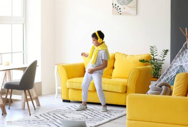 Dizüstü bilgisayarı olan şirin bir çocuk evde dans etmeyi öğreniyor.