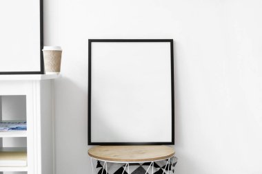 Beyaz duvarın yanındaki masada boş çerçeve