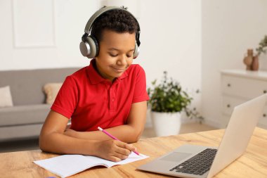Küçük Afro-Amerikalı çocuk evde online çalışıyor.