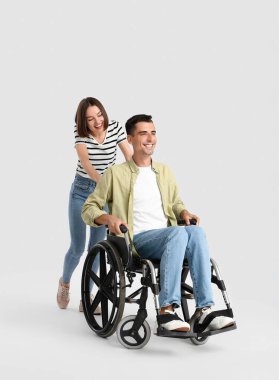 Young man in wheelchair and his wife on light background clipart