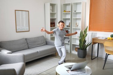 Dizüstü bilgisayarı olan komik çocuk evde dans etmeyi öğreniyor.