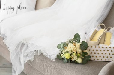 Güzel bir buket, gelinlik ve kanepede ayakkabılar.