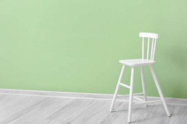 Yeşil duvarın yanındaki çocuklar için beyaz sandalye