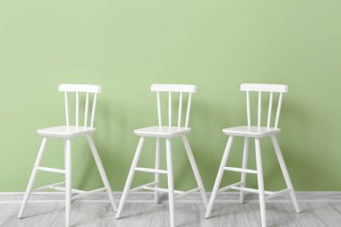 Çocuk odasındaki yeşil duvarın yanındaki beyaz modern sandalyeler