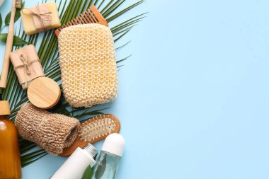 Lif süngerli banyo malzemeleri ve mavi arka planda palmiye yaprağı.