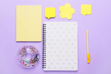 Leylak arkaplanı üzerine yapışkan not kağıtları içeren bir kırtasiye seti