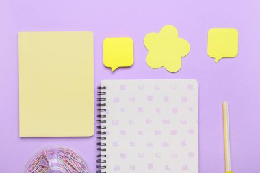 Leylak arkaplanı üzerine yapışkan not kağıtları içeren bir kırtasiye seti