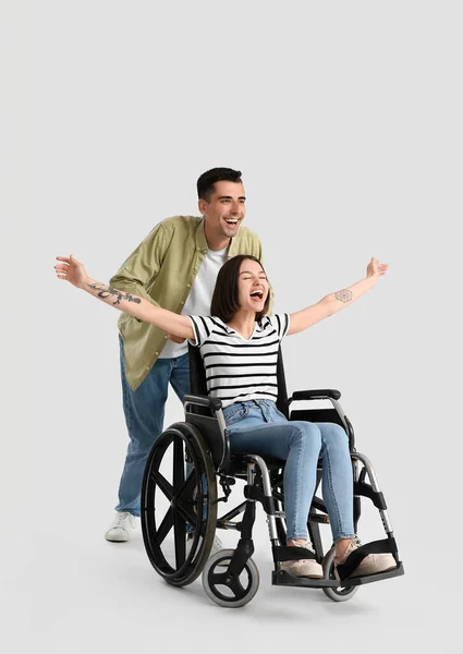車椅子の若い女性と光の背景の夫 — ストック写真