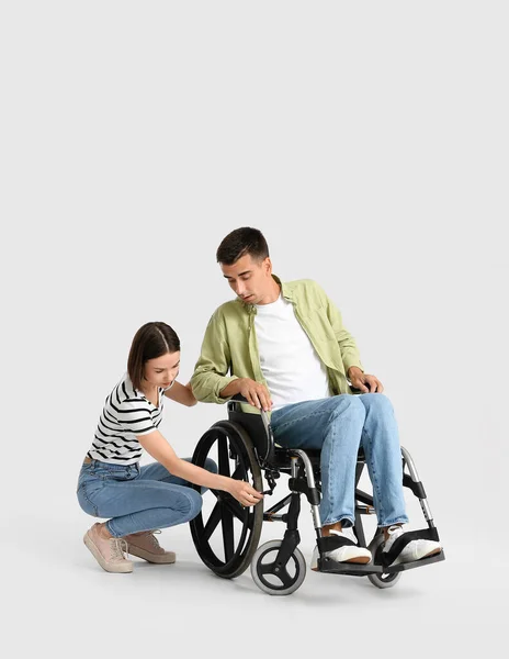年轻女子和她的丈夫在浅色背景的轮椅上有问题 — 图库照片